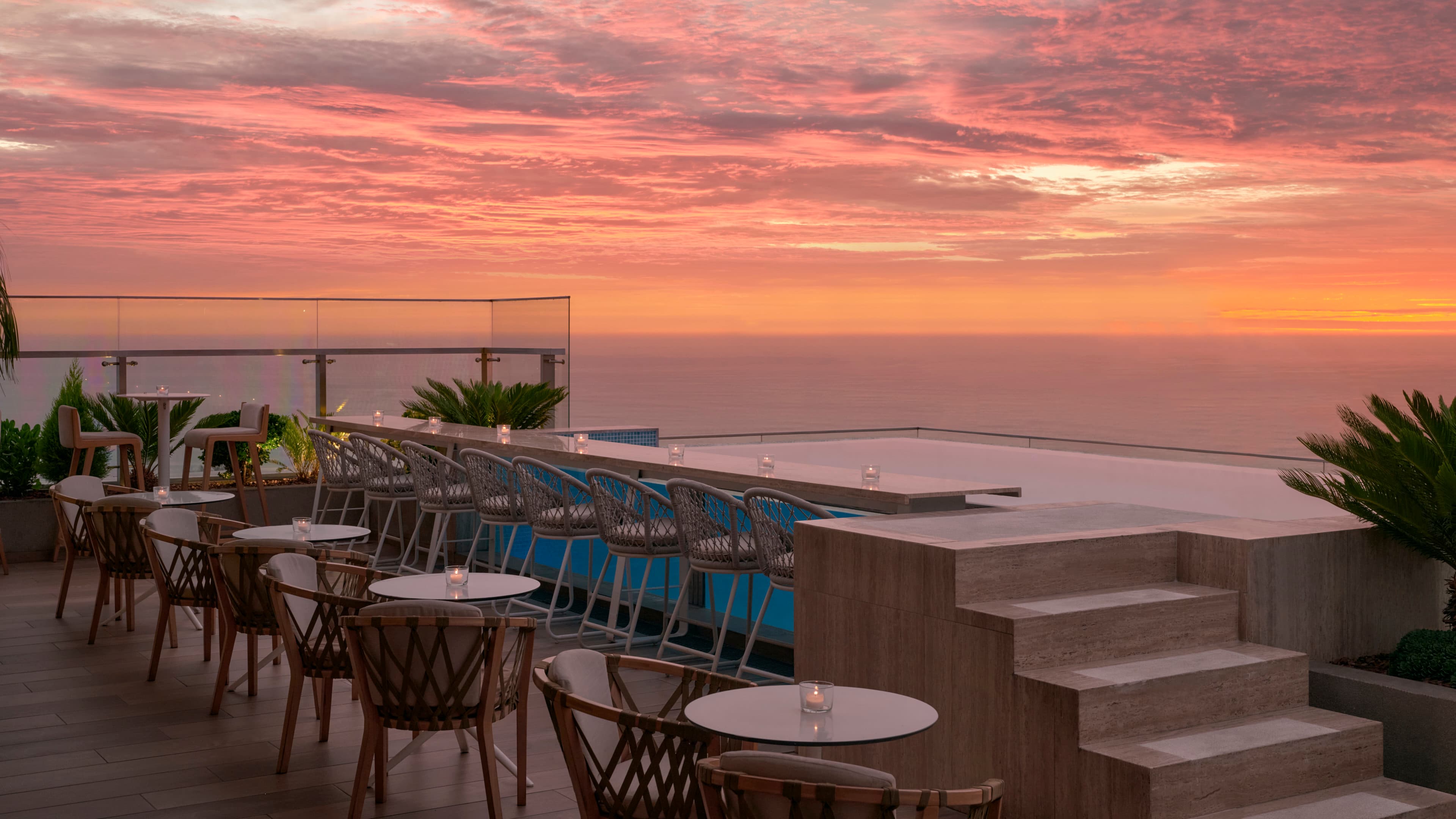 Enjoy poolside tapas with stunning ocean views at sunset.